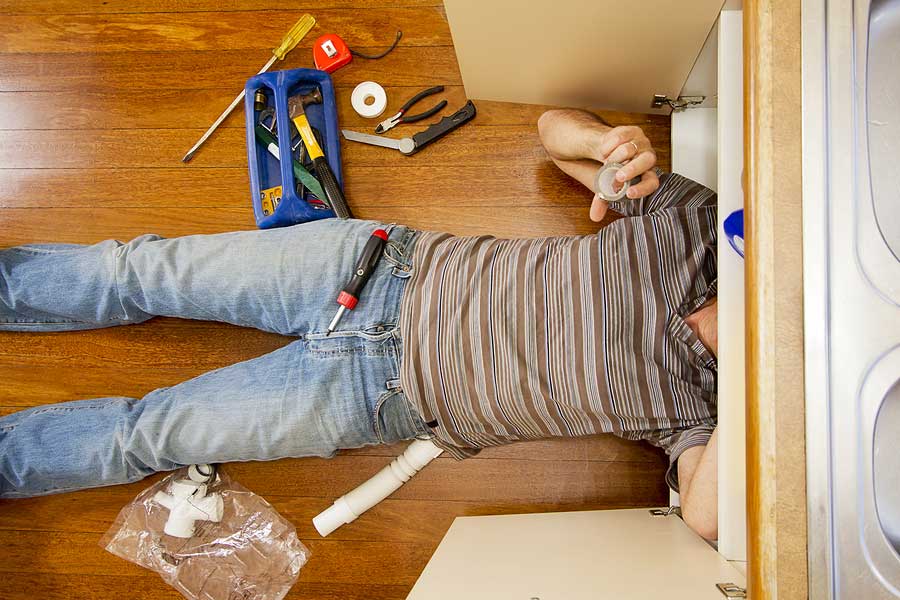 man under sink fixing plumbing